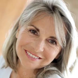 Smiling woman with shoulder-length gray-blond hair, looking at the camera.